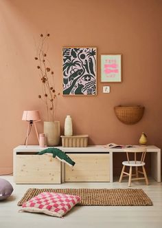 a living room with pink walls and furniture in the corner, including a white dresser