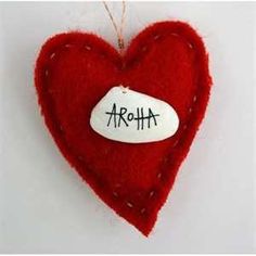 a red felt heart with the word aroha written in black ink on it