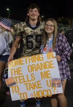 two people holding a sign that says something in the orange tells me to take us to hoo