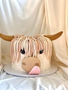 a cake decorated to look like a cow's head with long hair and pink tongue