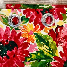 two metal buttons are attached to a colorful flowered fabric with red and yellow flowers