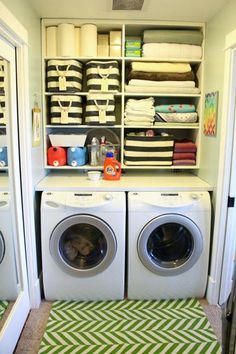 a washer and dryer in a small room with lots of towels on the shelves