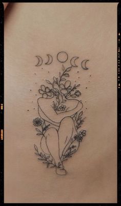 the back of a woman's stomach with flowers and moon tattoos on her ribs