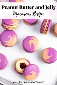 purple and yellow macaroons with peanut butter and jelly in the middle on a baking sheet