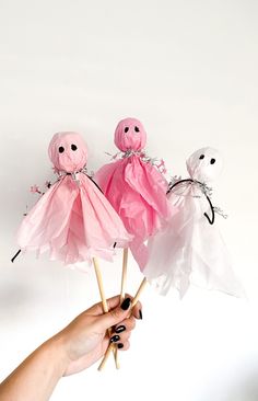 three pink and white paper ghost lollipops held up in front of the camera