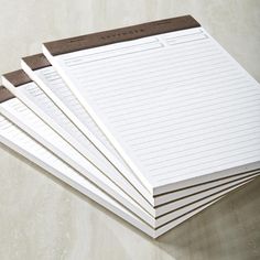 five lined notepads sitting on top of each other in front of a marble background