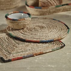 three woven baskets sitting on top of each other next to a white candle in a bowl