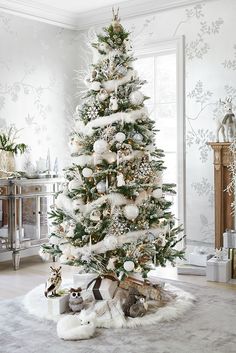 a decorated christmas tree in the corner of a living room with white and silver decor