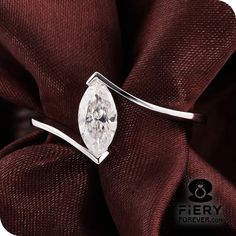 a white diamond ring sitting on top of a red cloth