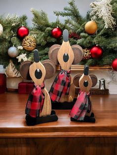 three wooden mouses are sitting on a table in front of a christmas tree with ornaments