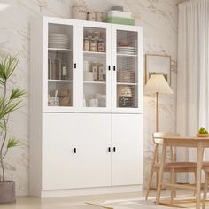 a white cabinet with glass doors next to a table and chair in a living room