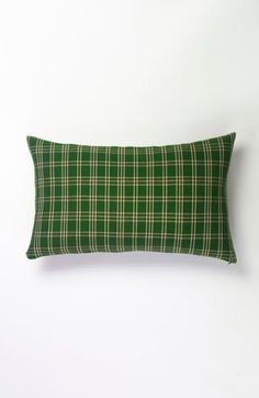 a green plaid pillow on a white wall