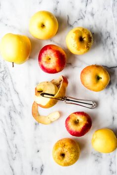 apples and an apple peel on a marble counter top with a pair of tongs