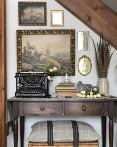 a desk with an old typewriter, flowers and pictures on the wall above it