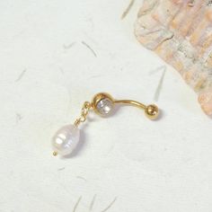 a close up of a pair of earrings on a white surface next to a seashell