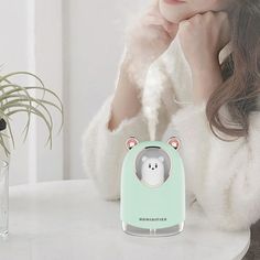 a woman sitting at a table with a bear shaped toaster in front of her