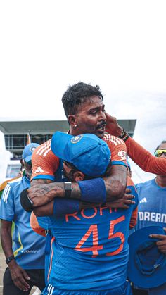 two men are hugging each other in the middle of a group of people wearing blue and orange uniforms