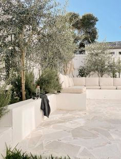 an outdoor living area with white furniture and trees