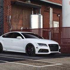 a white car parked in front of a brick building