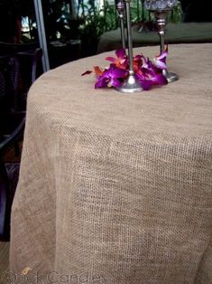 two candles on top of a table with purple flowers