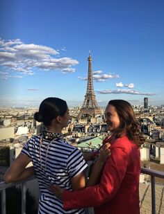 two women standing next to each other in front of the eiffel tower