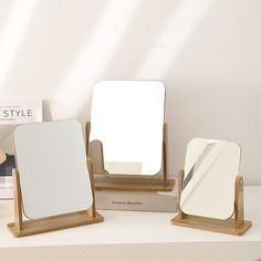 three wooden mirrors sitting on top of a white counter next to a box with a mirror in it