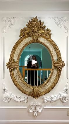 a mirror that is on the wall in front of a railing with a person looking at it