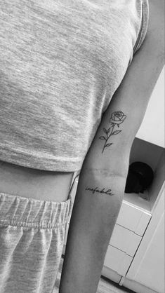 a black and white photo of a woman's arm with a rose tattoo on it