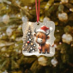 a christmas ornament hanging from a tree decorated with lights and a highland cow