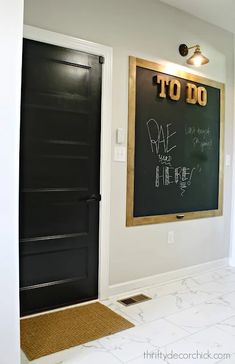 a chalkboard is hanging on the wall next to a black door in a white room