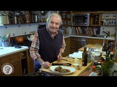 a man standing in a kitchen preparing food on top of a wooden cutting board with a knife and fork