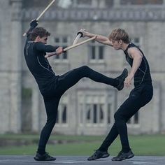 two young men practicing martial in front of an old building