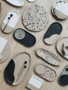 many different shapes and sizes of plates on a wooden table with black and white designs