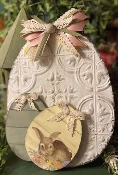 an easter egg with a bunny painted on it and a bow hanging from the top