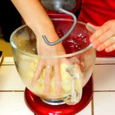 a person mixing batter in a red blender