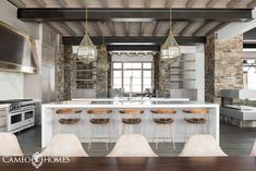 a large kitchen with an island and bar stools in the center, surrounded by stone walls