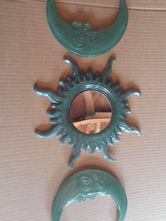 two mirrors are hanging on the wall near each other, one is shaped like a sun and the other has a crescent