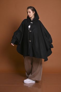 Black cape with hood. Nice soft 100% wool fabric Maxi cape with hood and fur fox. Maxi spring/ autumn cape. Two pockets. Hood. The cape has cuffs that close it on the sides. Model  wearring size S Heigth 173 cm- 5"8 inches Fabric: Soft wool 100% 🔔 Care: Only Dry Cleaning! Do not twist or fold! Do not wring! ▹ The style was originally designed and professionally constructed by me. Each item of my shop is specially packaged with a lot of concern! Handmade in a pet-free and smoke-free environment Oversized Hooded Cape For Cold Weather, Black Wool Poncho For Winter, Black Wool Hooded Outerwear, Hooded Wool Cape For Winter, Hooded Black Cape For Fall, Black Hooded Cape For Fall, Black Winter Cape For Outdoor, Black Winter Outdoor Cape, Hooded Wool Poncho For Fall