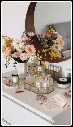 flowers are in vases on a dresser next to a mirror and other items that have been placed on it