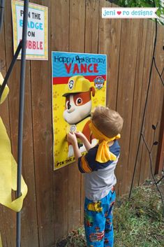 a little boy that is standing in front of a sign with a dog on it