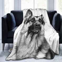 a black and white photo of a german shepherd dog on a blanket in front of a couch