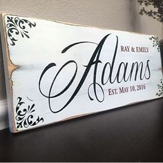 a wooden sign with the name and date on it sitting on a table next to a potted plant