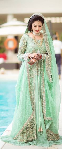 a woman in a green dress standing next to a pool