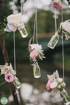 flowers in vases hanging from strings outside