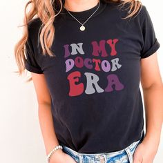 a woman wearing a black shirt with the words in my doctor era printed on it