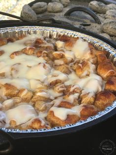 a pan filled with some kind of food on top of a stove next to rocks