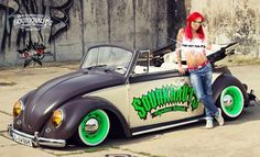 a woman with red hair sitting on top of an old car in front of a graffiti covered wall