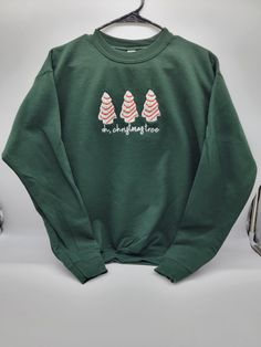 Product Description Oh Christmas Tree Cakes Embroidered Sweatshirt This Oh, Christmas Tree Cakes Embroidered Sweatshirt is the perfect addition to your festive wardrobe. A cozy sweatshirt with a beautifully embroidered Christmas tree cakes design that adds a touch of holiday joy to any outfit. This sweatshirt is so soft and comfortable that you'll want to wear it all day long. PRODUCT DETAILS: Unisex Sweatshirt: Gildan 18000 Material: *6 oz., 50% USA Cotton, 50% Polyester *DryBlend® fabric wicks moisture away from the body *Made with 50% sustainably and fairly grown USA cotton Feature: *Welt-knit collar and cuffs *Double-needle stitched hemmed bottom *Three-button placket *Tear away label *Dyed-to-match buttons *Gildan's manufacturing process utilizes 45% renewable energy *Gildan's Communi Little Debbie Christmas Tree, Christmas Tree Cakes, Cakes Design, O Christmas Tree, Little Debbie, Oh Christmas Tree, Christmas Tree Cake, Embroidered Christmas, Tree Cakes