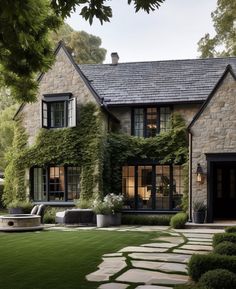 a stone house with ivy growing on it's walls and windows in the front yard