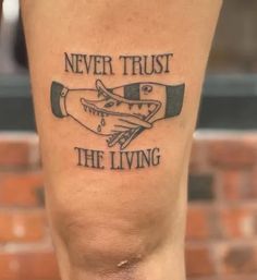 a person with a tattoo on their leg that says never trust the living above it